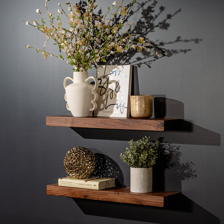 Black walnut floating shelves on a charcoal wall with dried flowers and decor